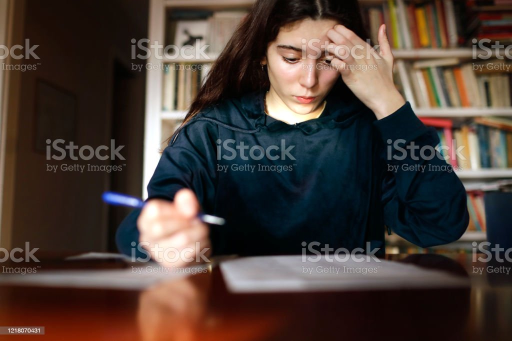 Teenage girl studying in the library, preparing for a test exam